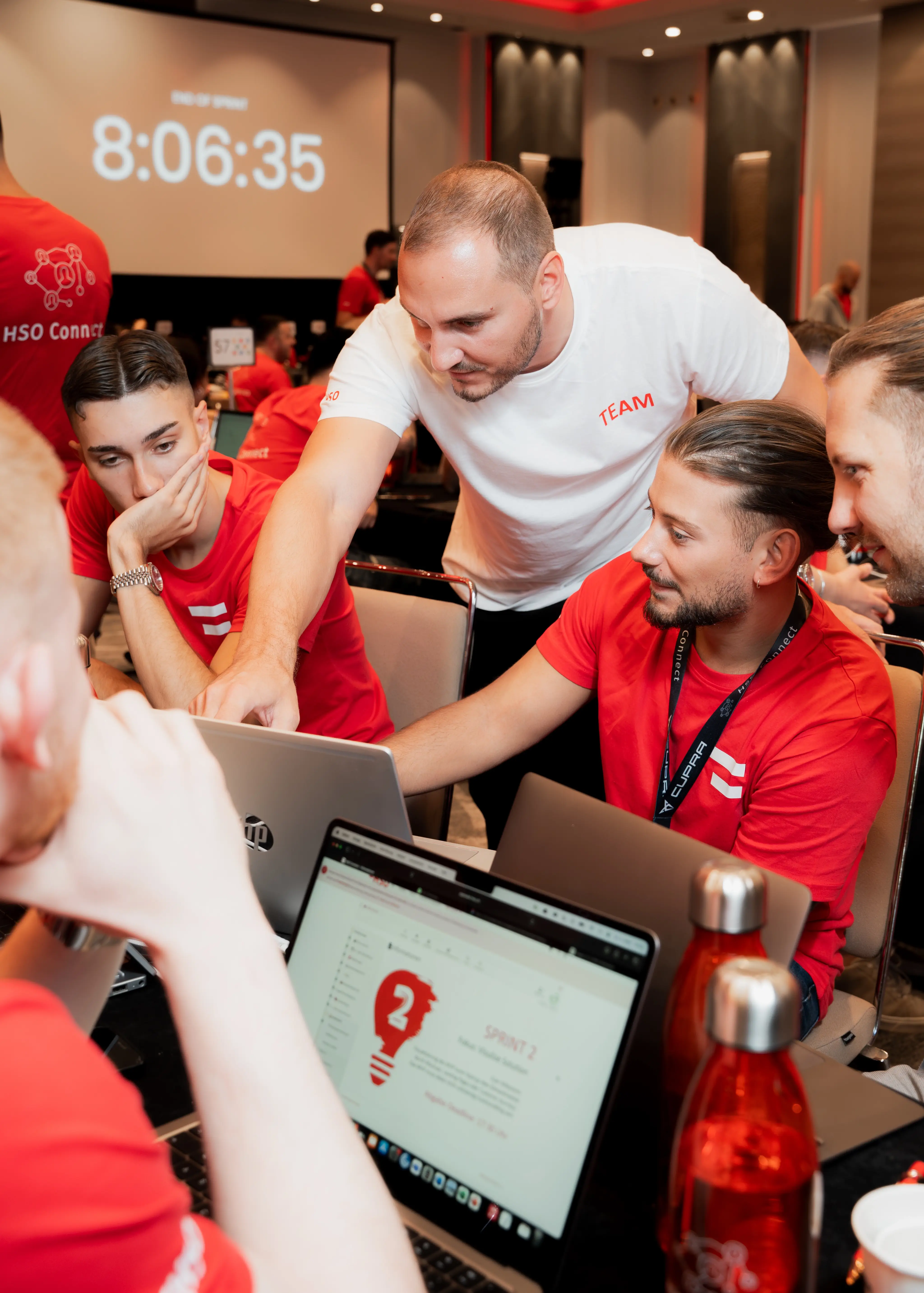 Ein Coach unterstützt ein Team von Studierenden am Laptop